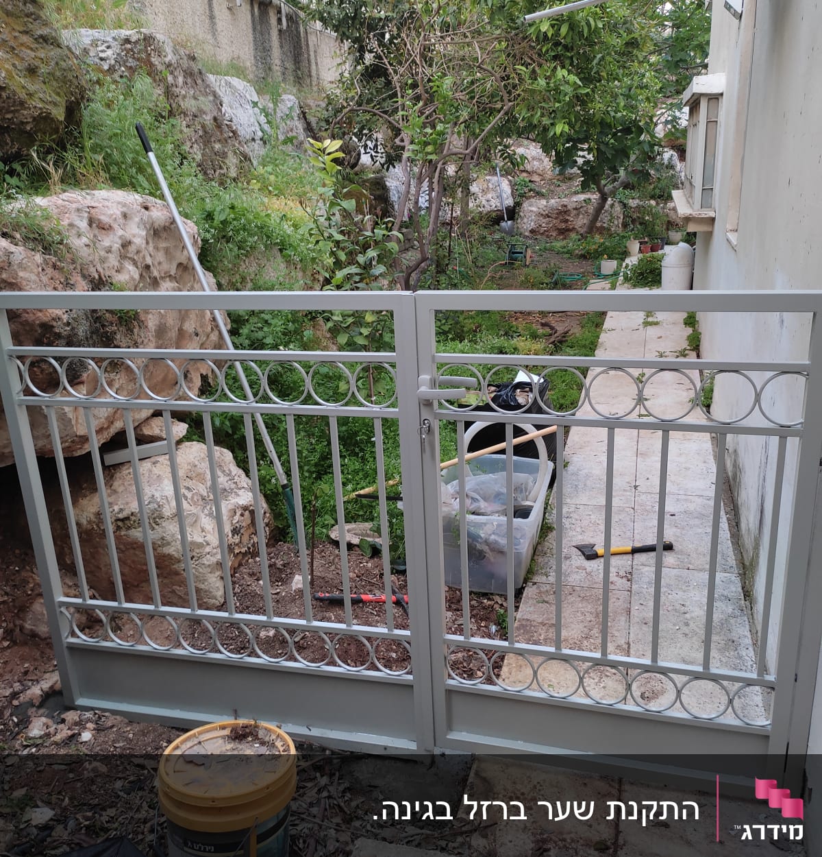שער מתכת אפור עם עיטורים עגולים בגינה